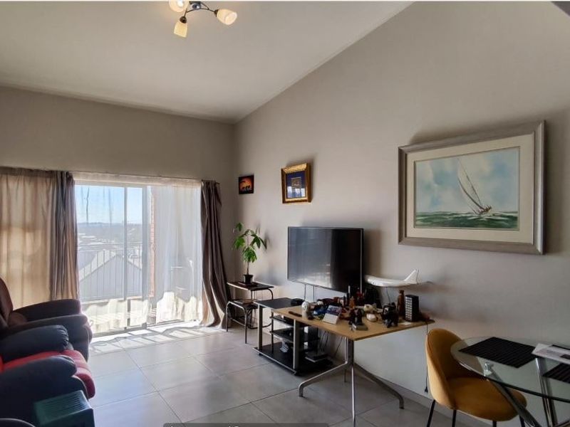 A living room featuring tiled flooring and a large sliding glass door that provides natural light and access to the exterior.