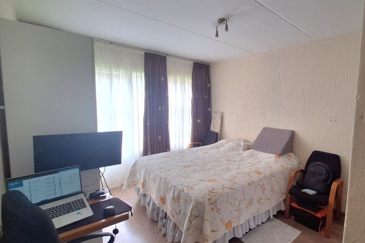 A functional bedroom featuring laminate flooring and textured walls, offering a blank canvas for potential cosmetic updates and interior design improvements.