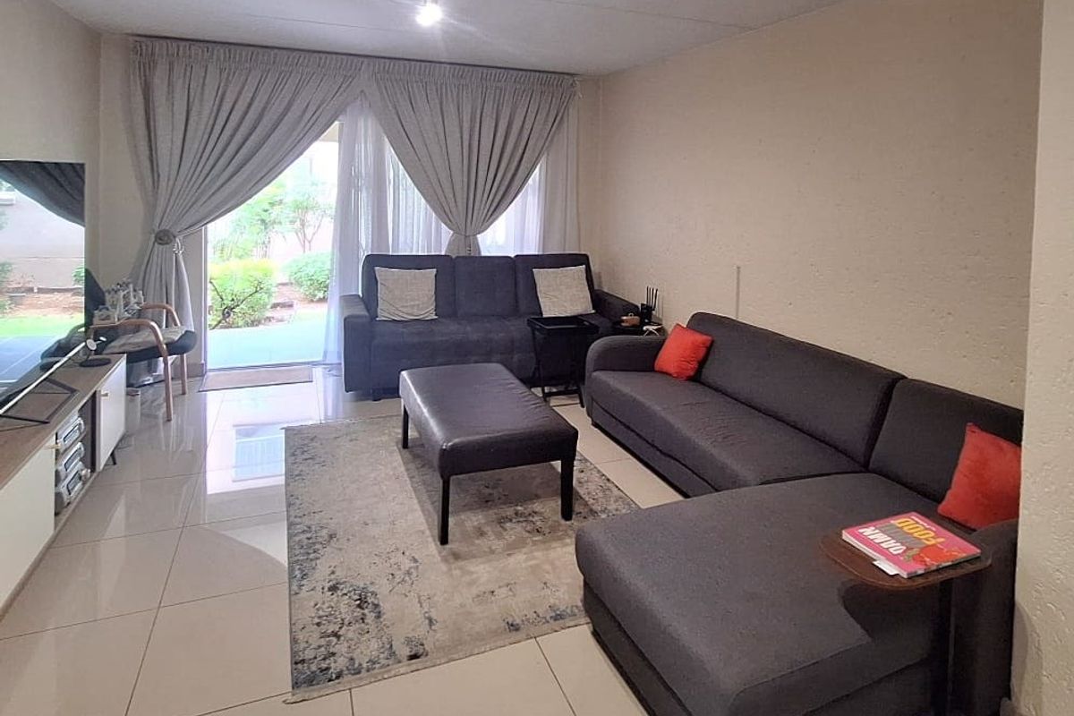 A comfortable living room featuring large format floor tiles and a sliding glass door providing direct access to the outdoor area.