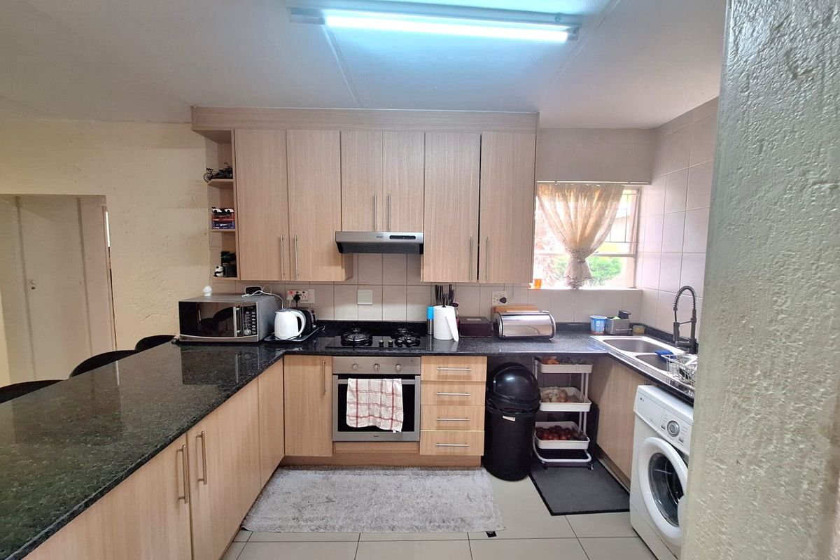 Functional kitchen featuring light wood cabinetry, granite countertops, built-in oven with gas hob, and tiled finishes throughout.