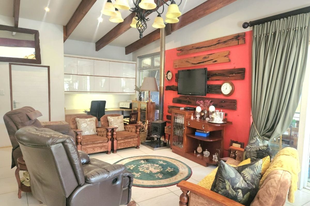 Spacious living room featuring exposed timber ceiling beams, a freestanding wood-burning fireplace, and built-in cabinetry, offering a warm and functional living space.