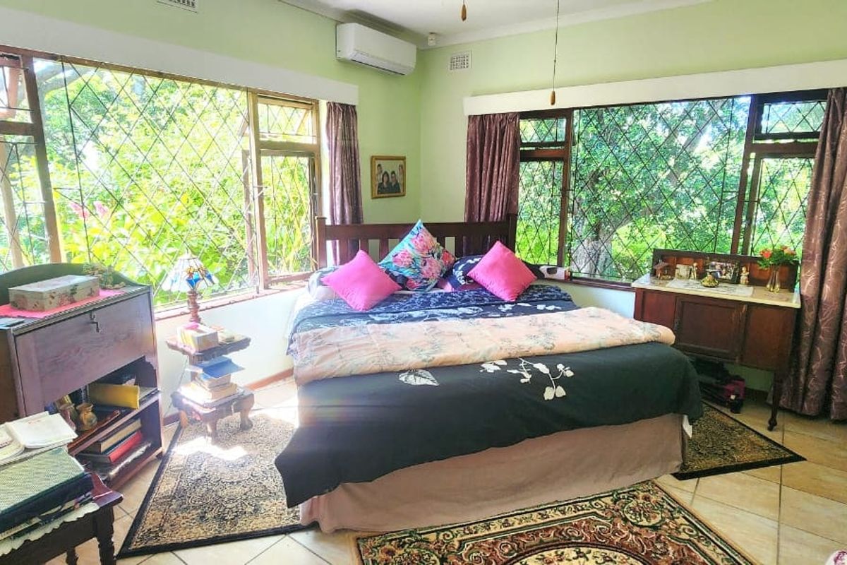 Spacious bedroom featuring tiled flooring, built-in cabinetry, and large windows with security bars, complemented by a wall-mounted split-system air conditioner.