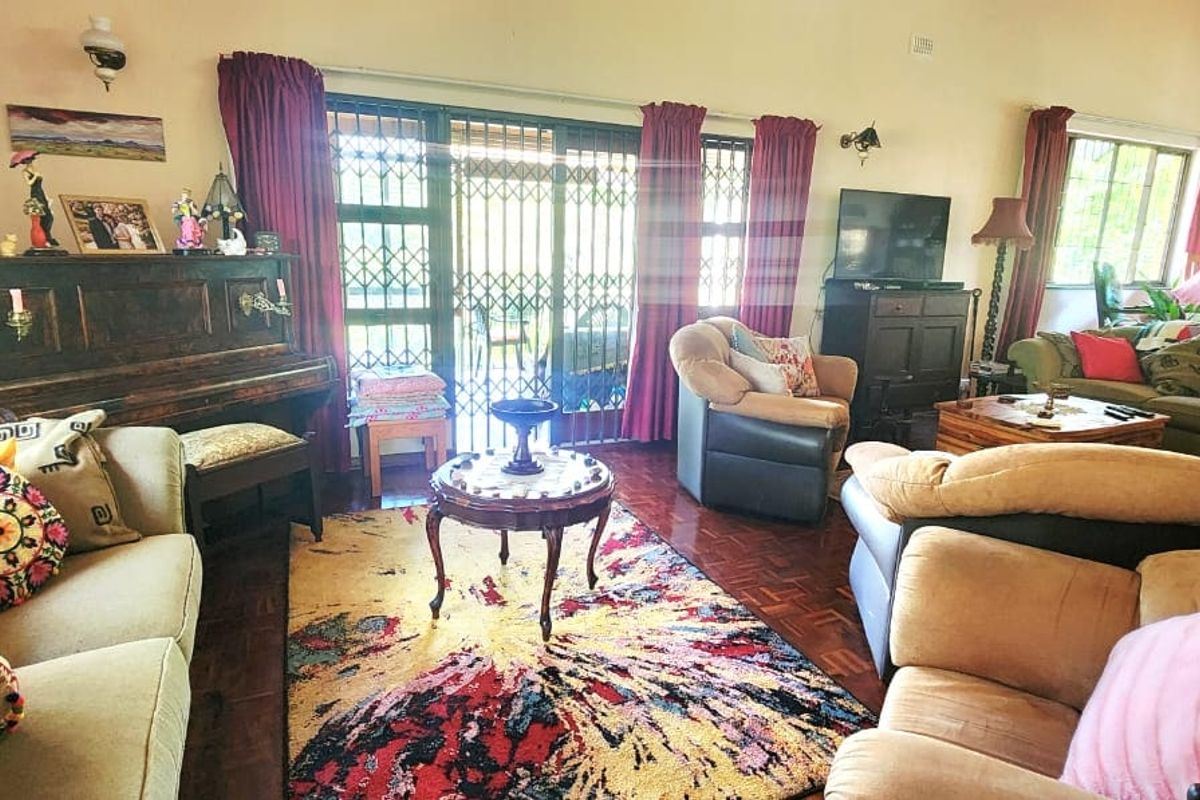 Spacious living room featuring warm parquet flooring, a vaulted timber ceiling, and sliding glass doors providing access to the outdoor area.