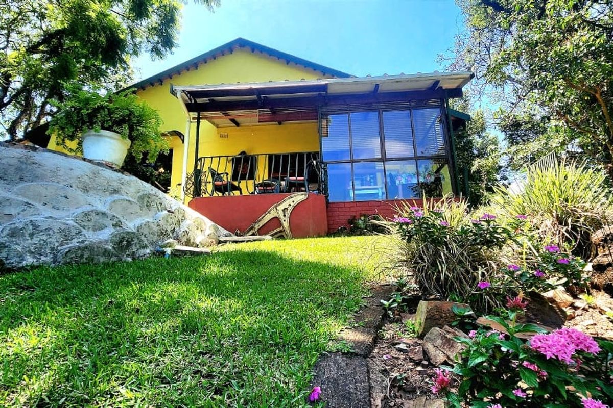 Rear view of the property featuring a covered patio, enclosed sunroom, and a landscaped garden with stone retaining features.