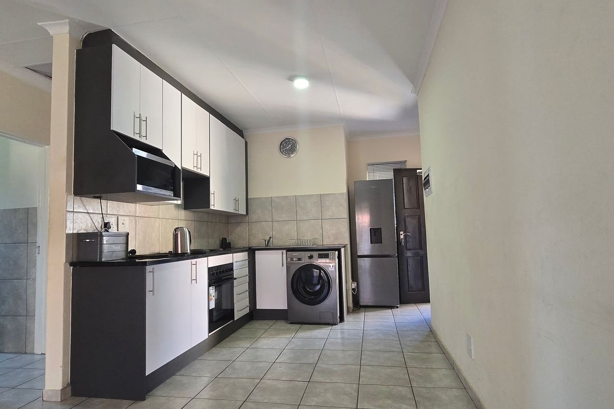 Modern kitchen featuring two-tone cabinetry, tiled backsplash, built-in oven and hob, and dedicated plumbing for laundry appliances.