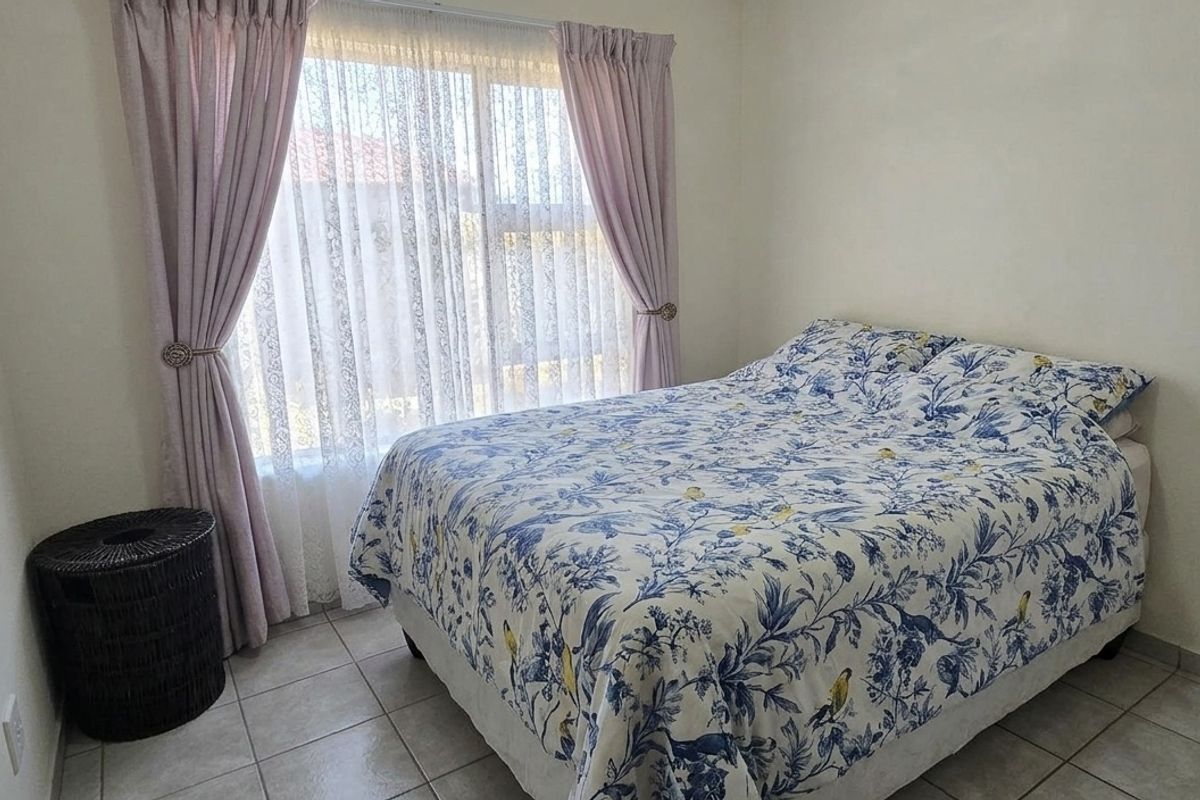 A functional bedroom featuring tiled flooring and a large sliding window, providing natural light and a neutral foundation for interior design.