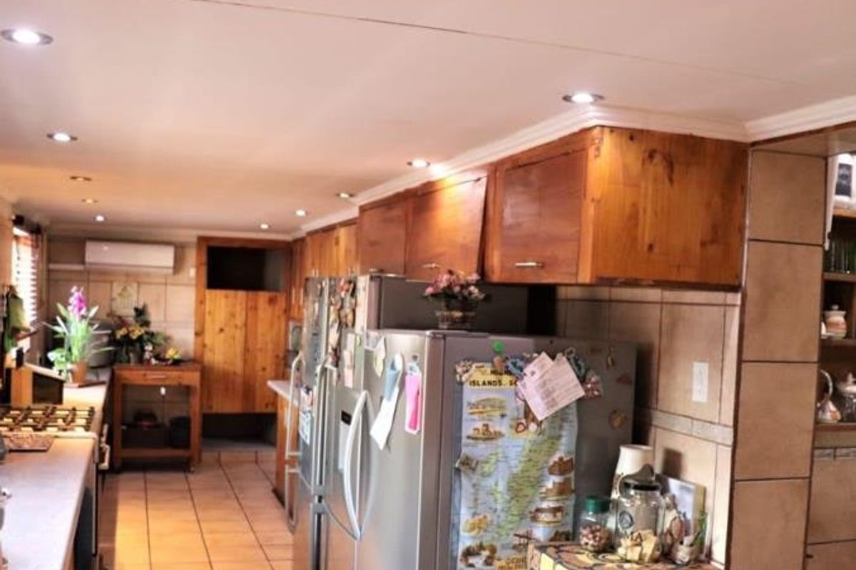 A functional kitchen featuring wooden cabinetry, tiled flooring, and a tiled backsplash, equipped with a split-system air conditioner and recessed lighting.