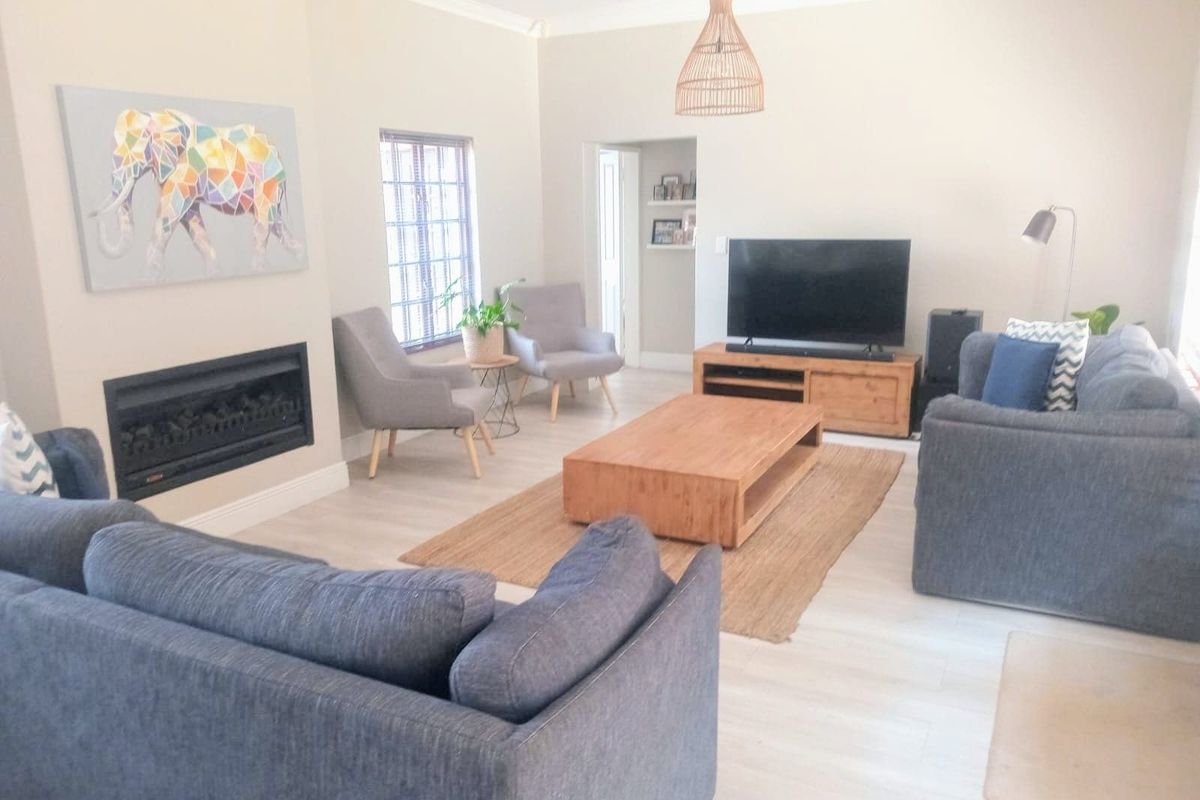 A bright and spacious living room featuring light-toned laminate flooring, a modern built-in fireplace, and neutral wall finishes.