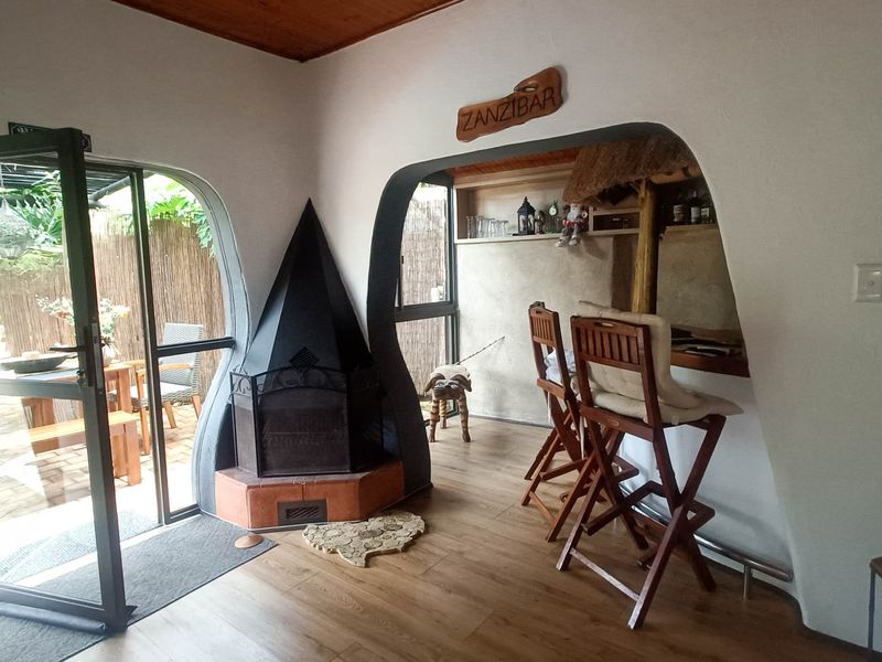 A unique indoor bar area featuring a distinctive freestanding fireplace, built-in bar counter, timber flooring, and direct access to an outdoor patio.