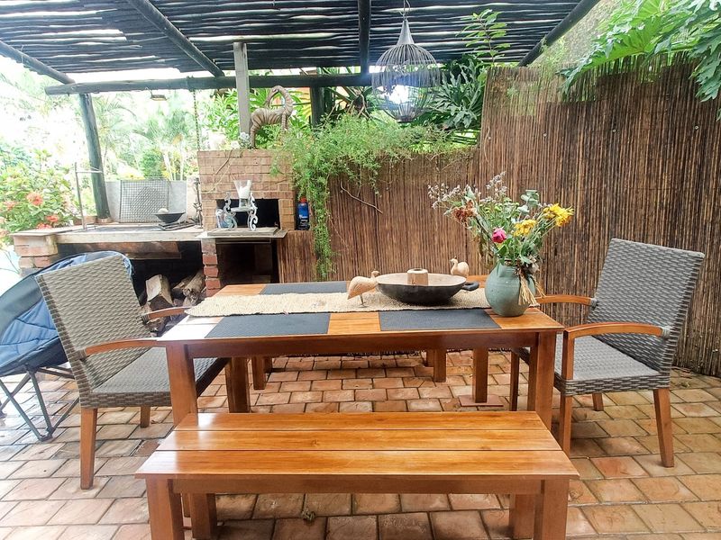 Covered outdoor patio area featuring a brick built-in braai, timber pergola structure, and brick paved flooring, ideal for alfresco dining and entertaining.
