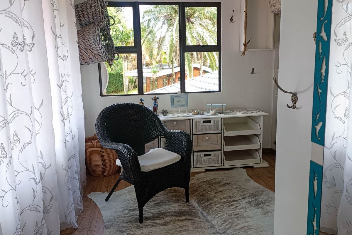 A bright bedroom featuring laminate flooring and large windows with views of the garden, offering a cozy and functional living space.