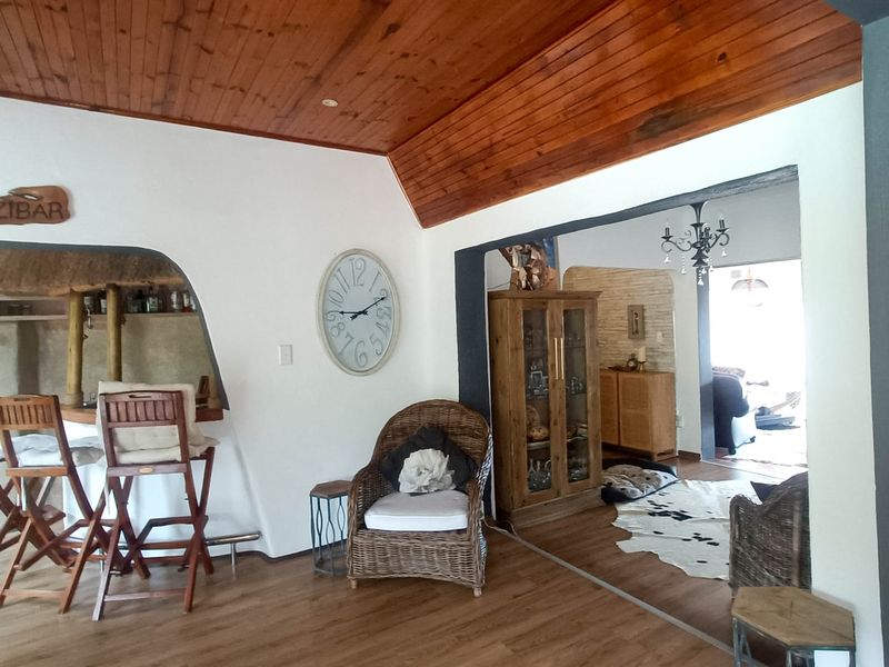 Open-plan living area featuring a timber-clad vaulted ceiling, laminate flooring, and a built-in bar counter with an arched opening.
