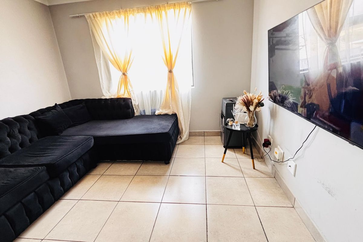 A living room featuring ceramic floor tiles and neutral wall finishes, providing a functional space for relaxation.