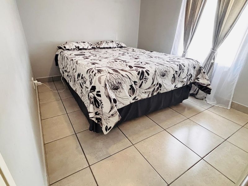 A functional bedroom featuring neutral wall finishes and tiled flooring, providing a clean and simple space.
