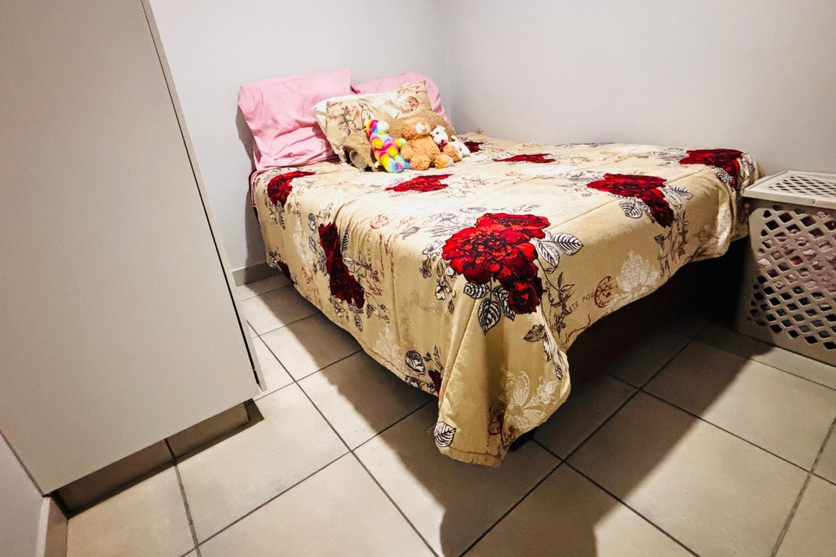 A compact bedroom featuring tiled flooring and a built-in wardrobe, providing functional storage space.