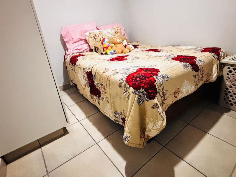 A compact bedroom featuring tiled flooring and a built-in wardrobe, providing functional storage space.