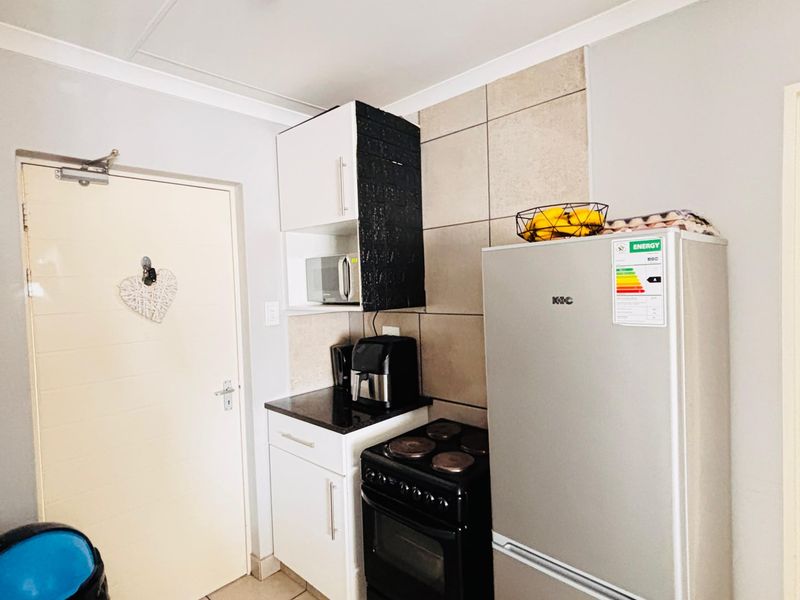 A compact kitchen area featuring built-in cabinetry, a tiled splashback, and a freestanding stove with oven.