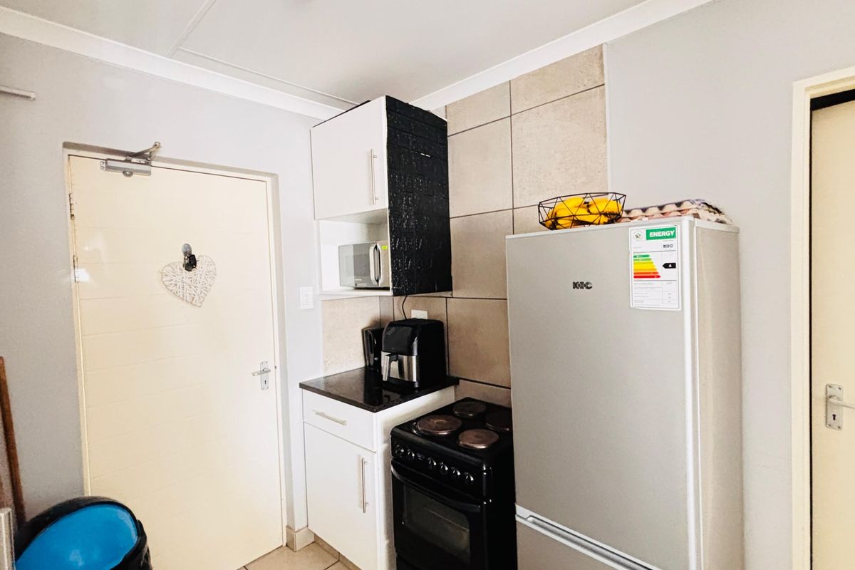 A compact kitchen area featuring built-in cabinetry, a tiled splashback, and a freestanding stove with oven.