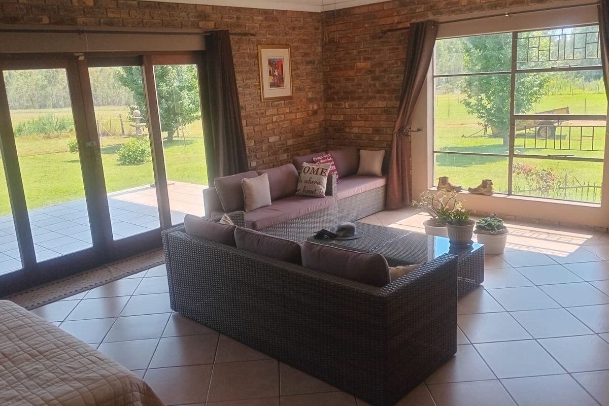Spacious living room featuring exposed brick walls, large windows, and sliding glass doors providing direct access to the outdoor patio and garden area.