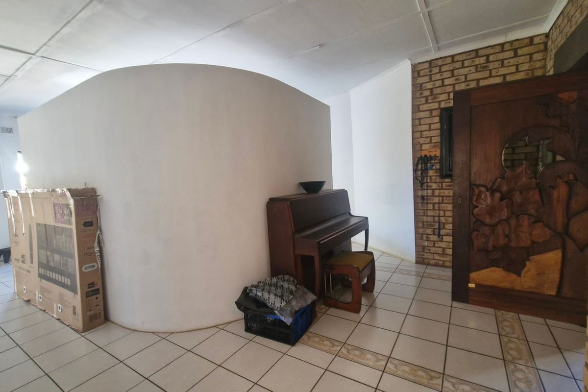 Living area featuring a curved partition wall, exposed brickwork, and ceramic tile flooring with a decorative carved wooden door.