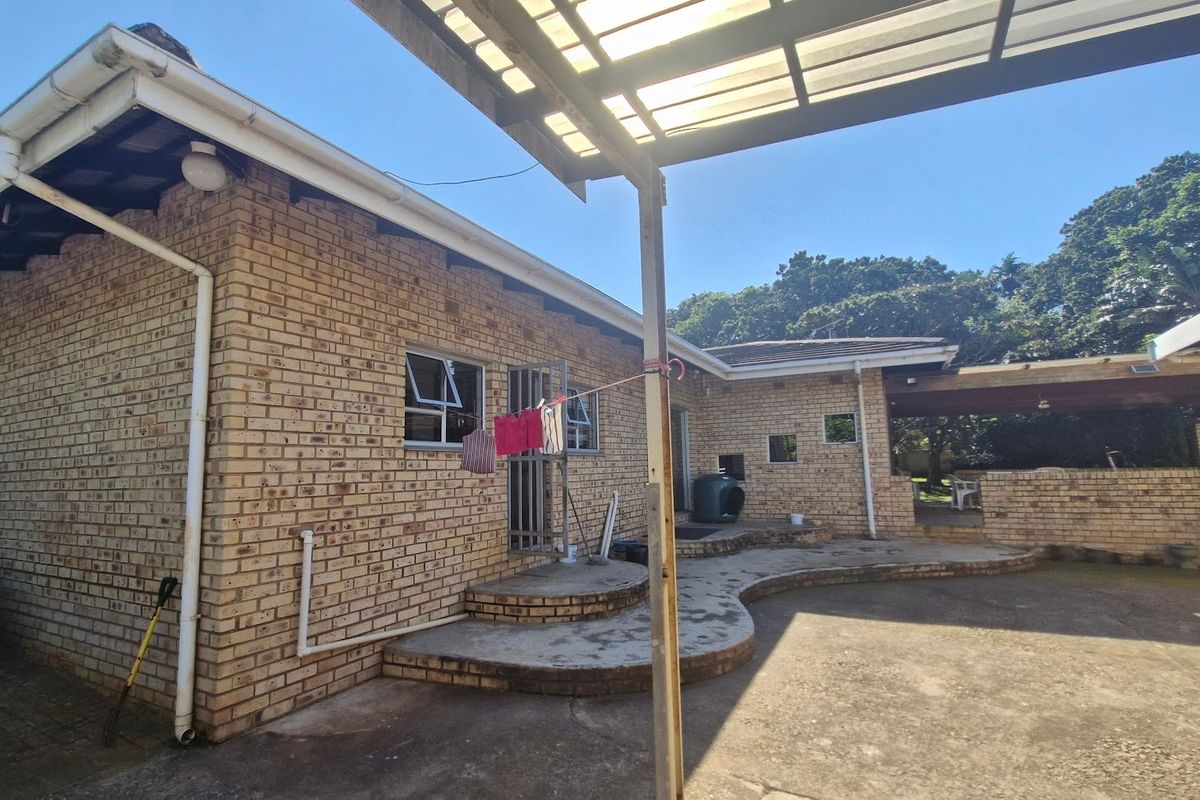 Rear exterior view of the house featuring a face brick facade, concrete patio area, and a covered pergola structure.