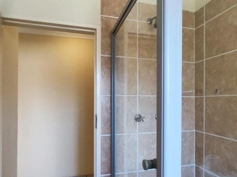 A functional bathroom featuring a tiled shower enclosure with a glass door and standard shower fixtures.