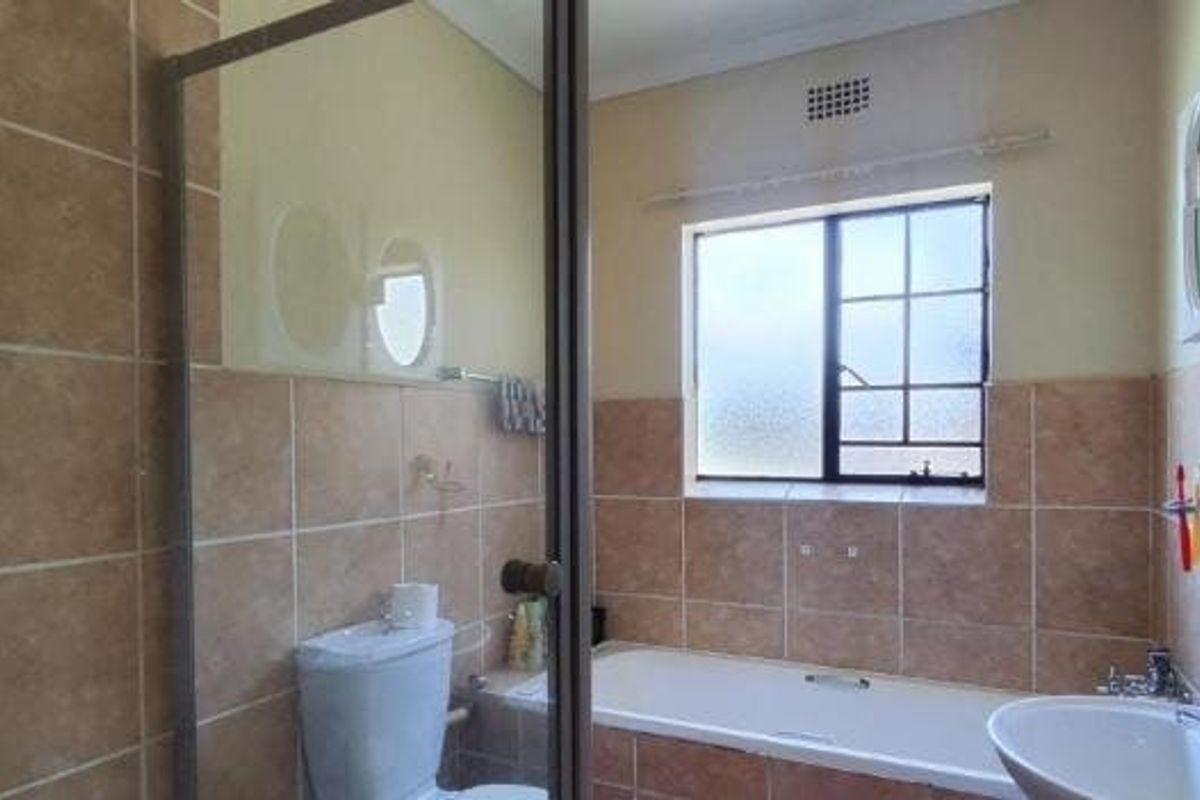 A functional bathroom featuring a bathtub, separate shower enclosure, toilet, and washbasin with neutral wall tiling.