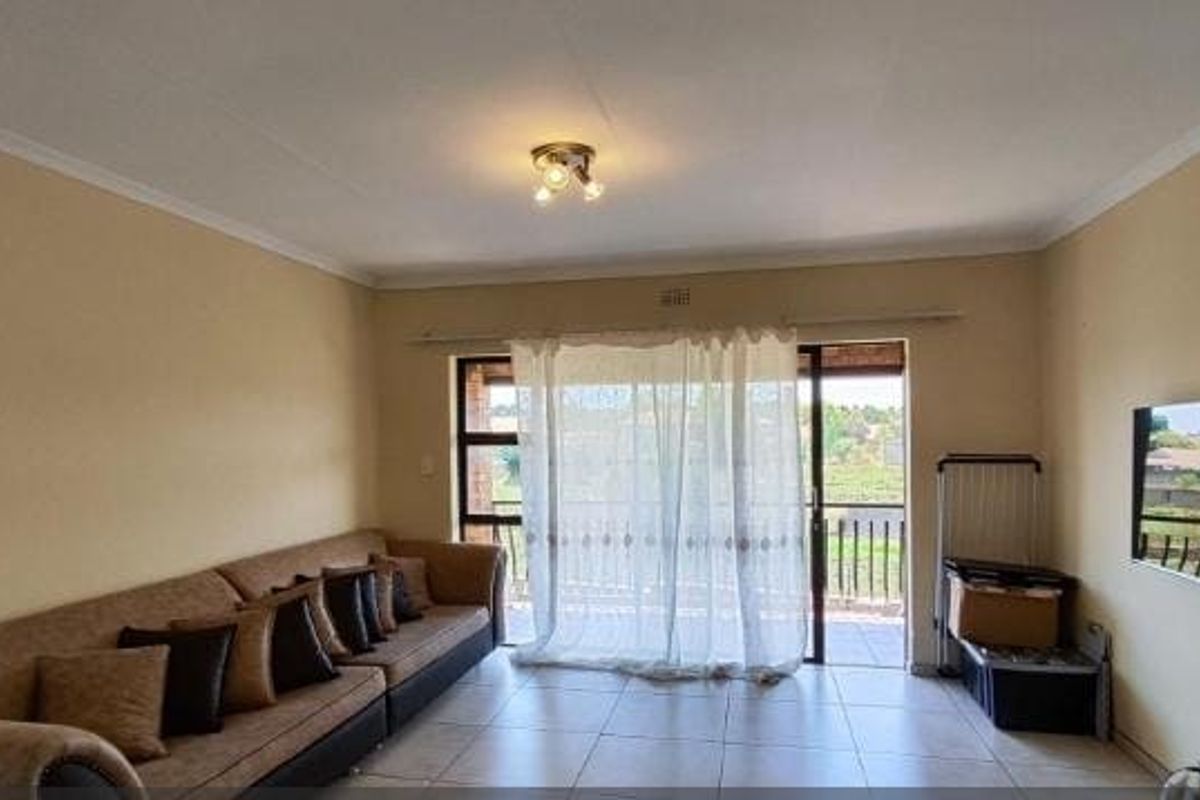 A spacious living room featuring tiled flooring and a large sliding glass door that provides access to an outdoor area.