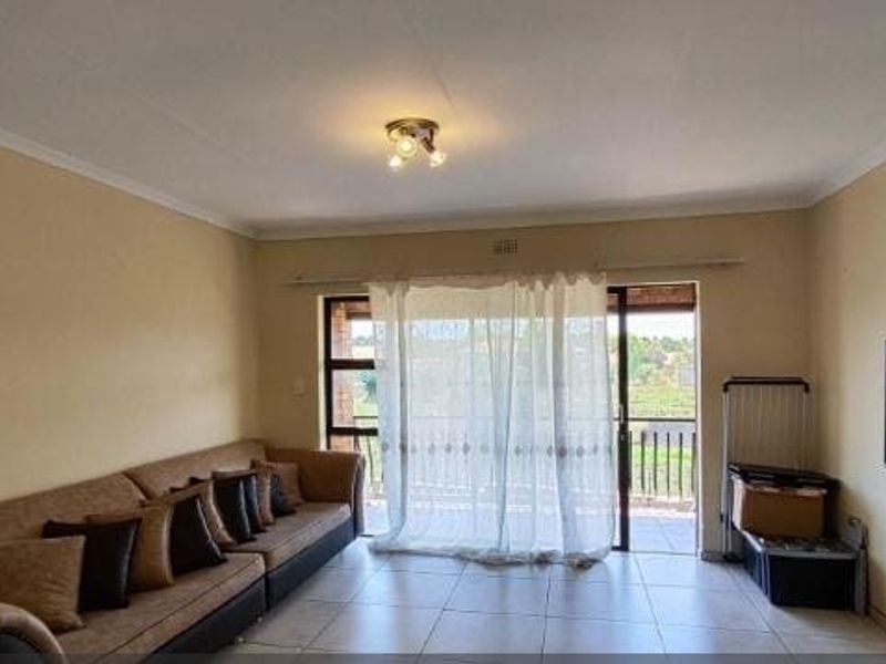 A spacious living room featuring tiled flooring and a large sliding glass door that provides access to an outdoor area.