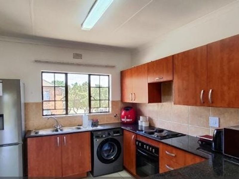 Functional kitchen featuring wooden cabinetry, granite countertops, tiled backsplash, and built-in oven with hob, offering practical workspace and storage.