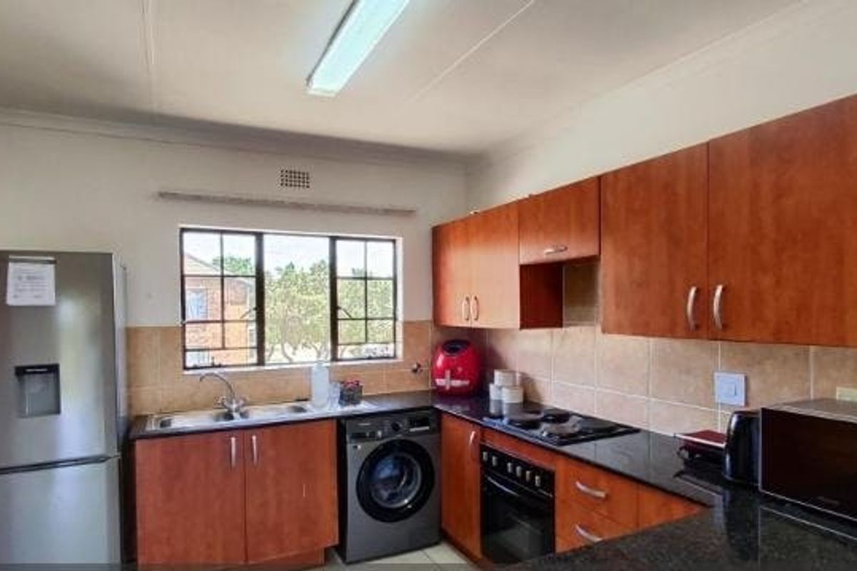 Functional kitchen featuring wooden cabinetry, granite countertops, tiled backsplash, and built-in oven with hob, offering practical workspace and storage.