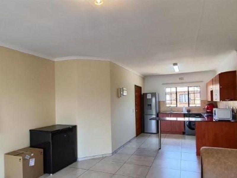 Open-plan living area featuring tiled flooring and a functional kitchen with built-in cabinetry and a breakfast bar.
