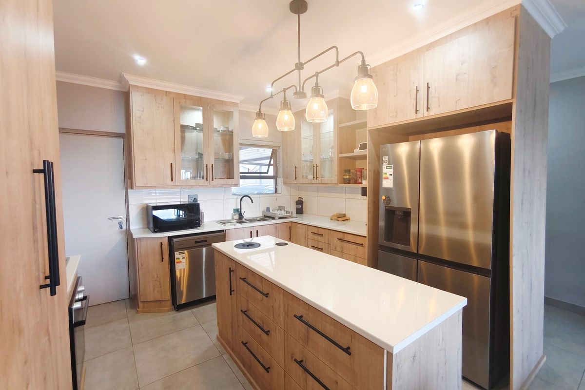 Modern kitchen featuring light wood cabinetry, quartz countertops, a central island, and high-quality finishes throughout.