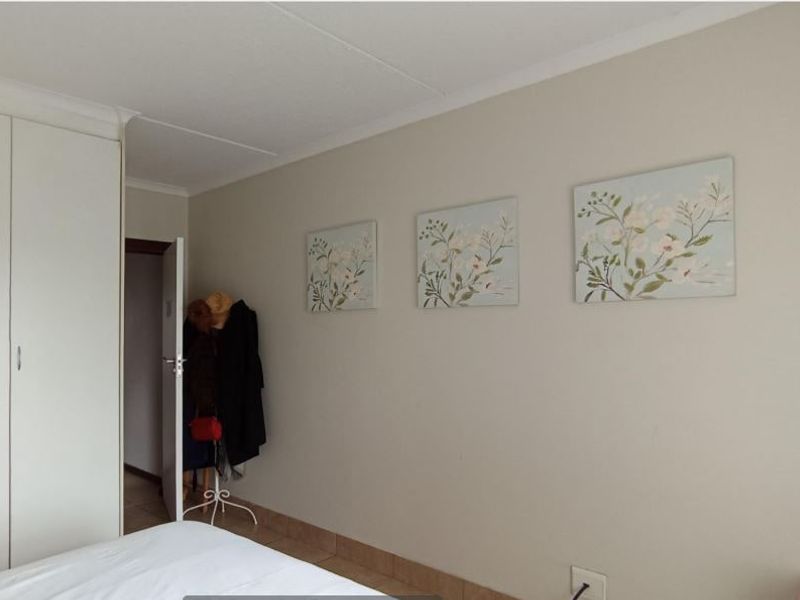 A bedroom featuring neutral walls, tiled flooring, and a built-in wardrobe with clean lines.