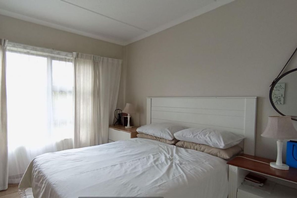 A well-lit bedroom featuring a large window with natural light and neutral wall finishes.