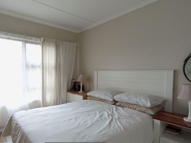 A well-lit bedroom featuring a large window with natural light and neutral wall finishes.