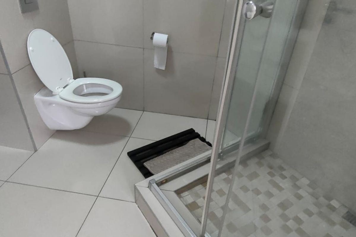 Modern bathroom featuring a wall-mounted toilet and a glass-enclosed shower with tiled flooring and neutral wall finishes.