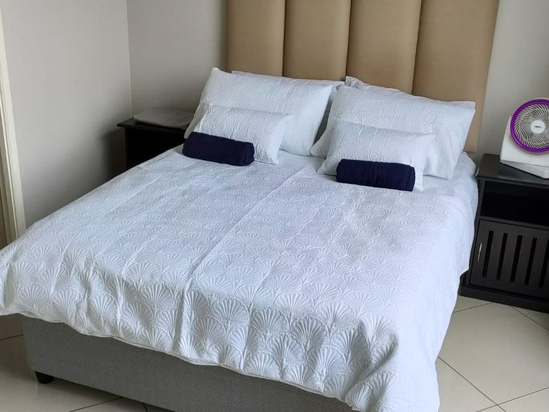 A well-maintained bedroom featuring tiled flooring, a neutral color palette, and an en-suite bathroom access.