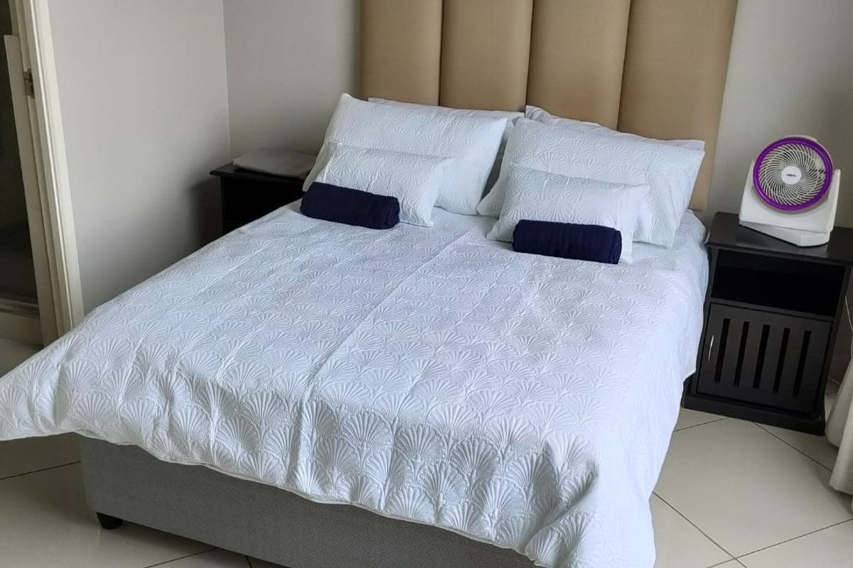 A well-maintained bedroom featuring tiled flooring, a neutral color palette, and an en-suite bathroom access.