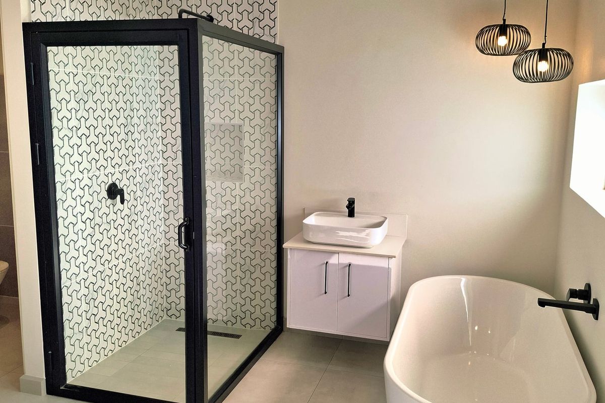 Modern bathroom featuring a sleek freestanding bathtub, a walk-in shower with black frame, patterned tile accents, and a contemporary wall-mounted vanity.