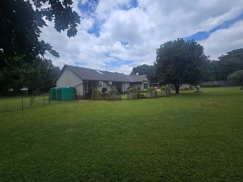 Spacious rear garden featuring a well-maintained lawn, mature trees, and exterior building elevation with installed water storage tanks and air conditioning units.