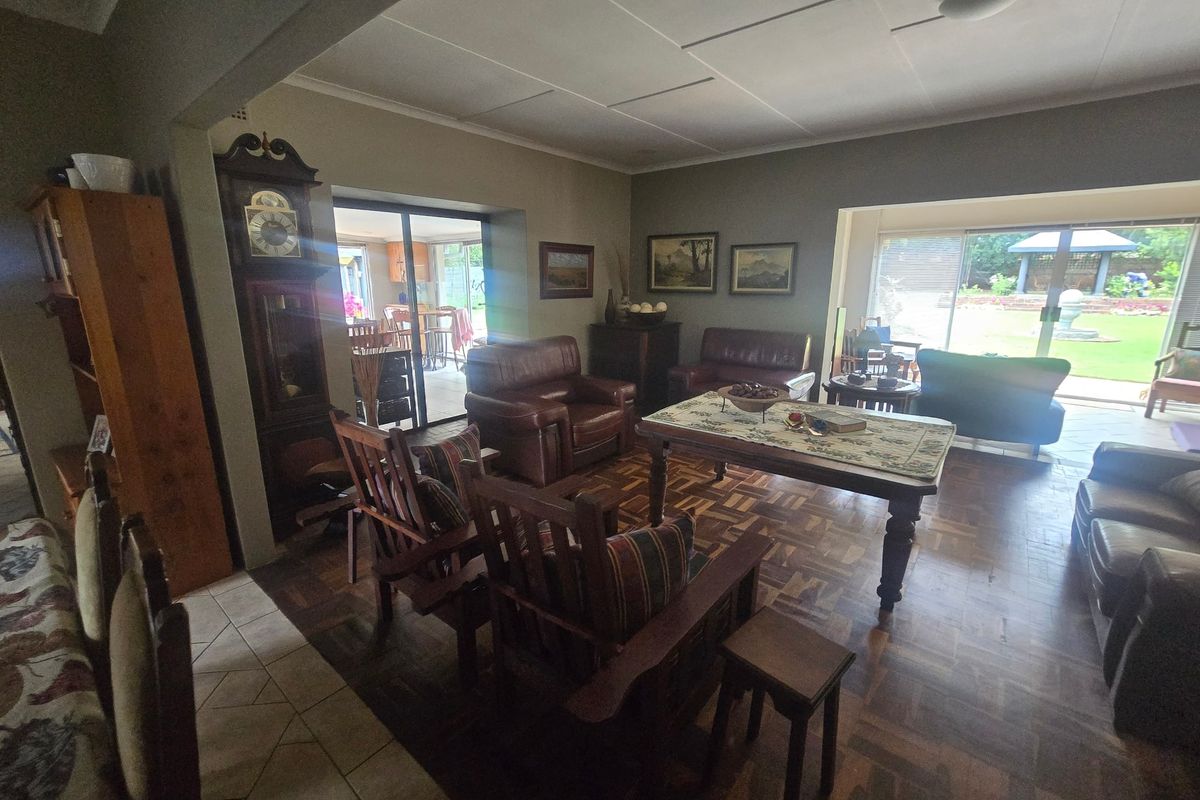 Spacious living room featuring classic parquet flooring, large sliding glass doors providing natural light, and direct access to the rear garden area.