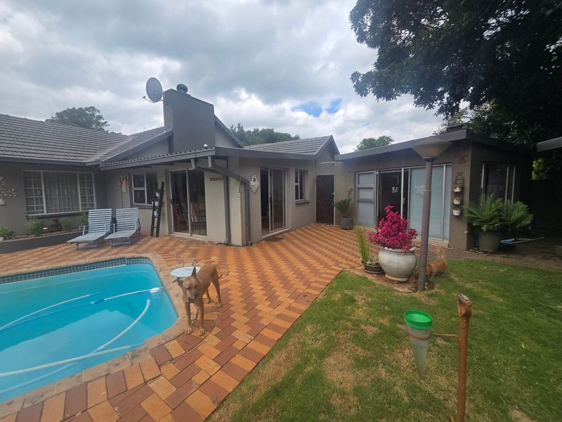 Rear exterior view featuring a swimming pool, paved patio area, and direct access to the house through sliding glass doors.