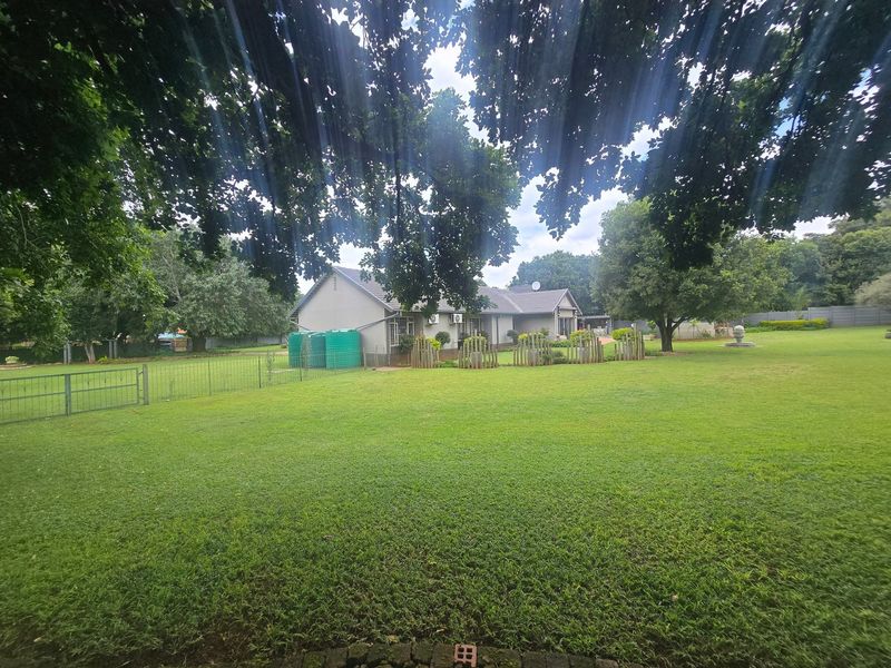 A spacious rear garden view featuring a well-maintained lawn, perimeter fencing, and water storage tanks adjacent to the main house structure.