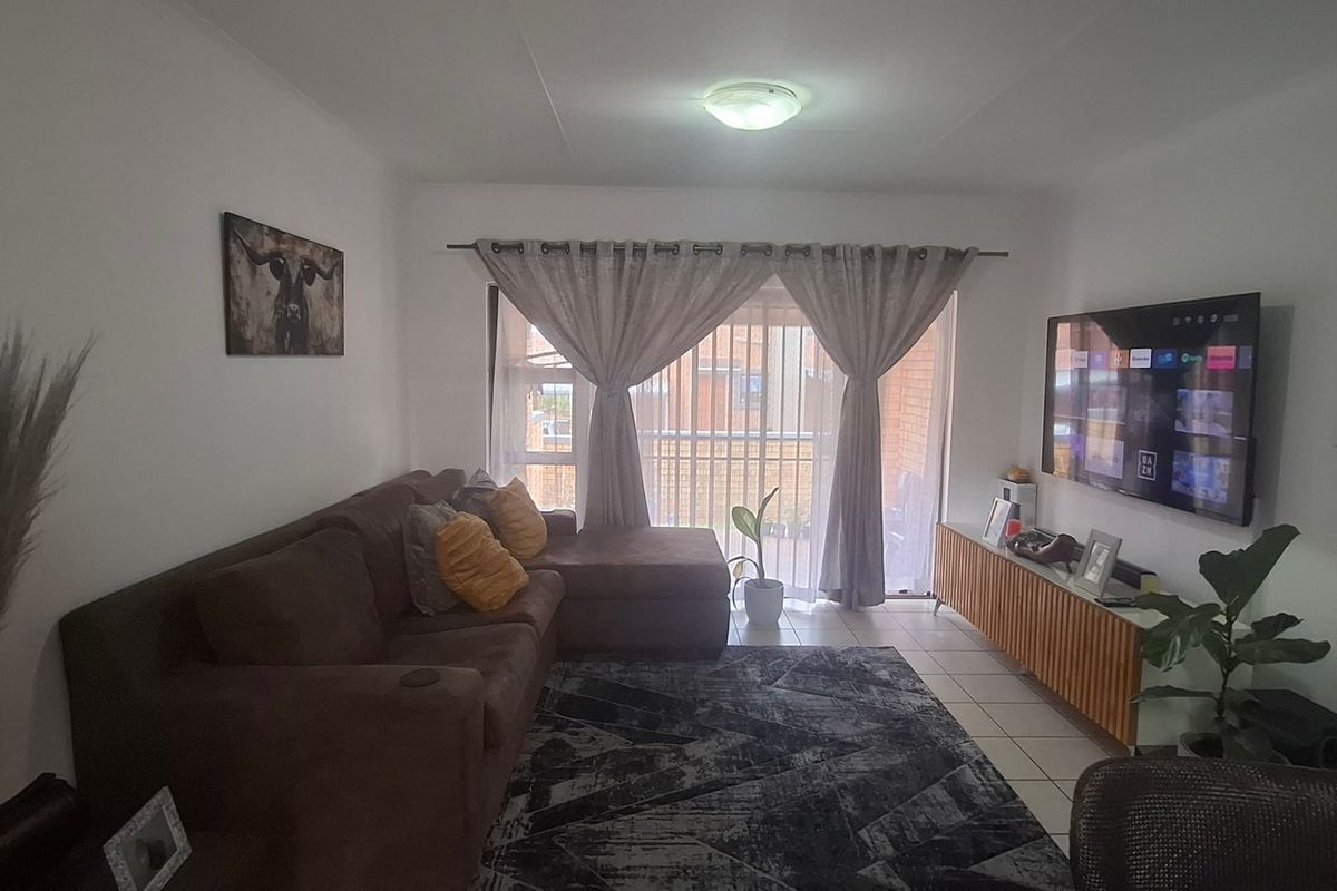 A comfortable living room featuring tiled flooring and a large sliding glass door that provides access to the outdoor area.