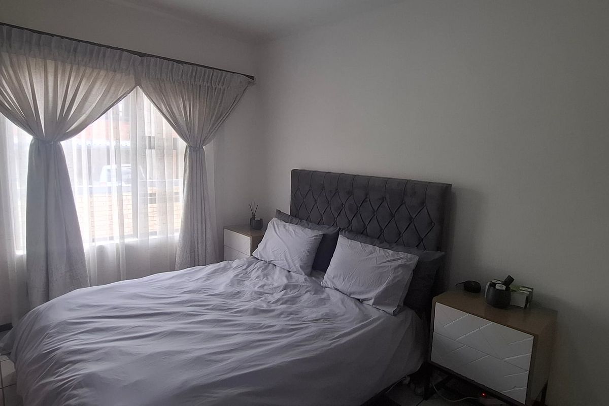 A functional bedroom featuring tiled flooring and built-in cupboards, providing a neutral space ready for personalization.