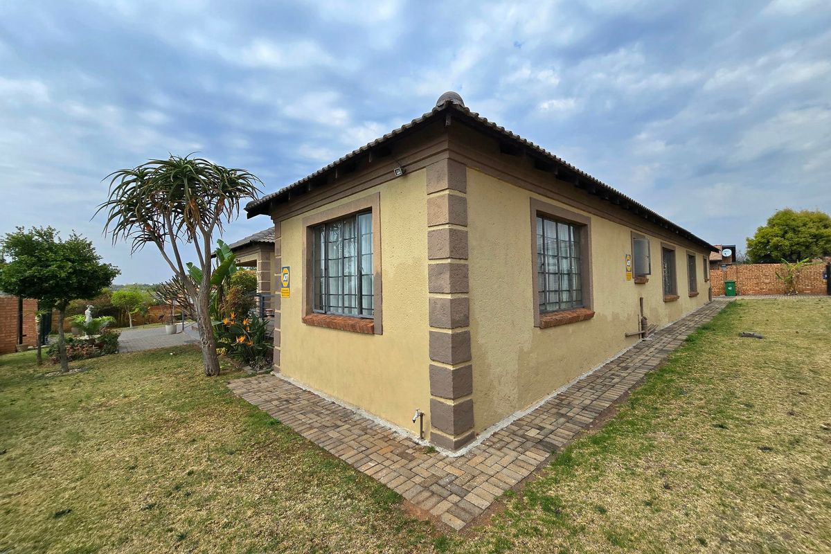 Rear exterior view of the house featuring a tiled roof, security bars on windows, and a brick-paved walkway surrounding the building perimeter.