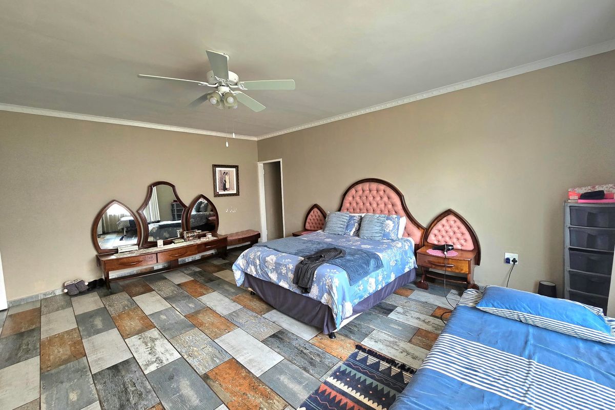 Spacious bedroom featuring unique wood-look tiled flooring, a ceiling fan, and decorative coving.