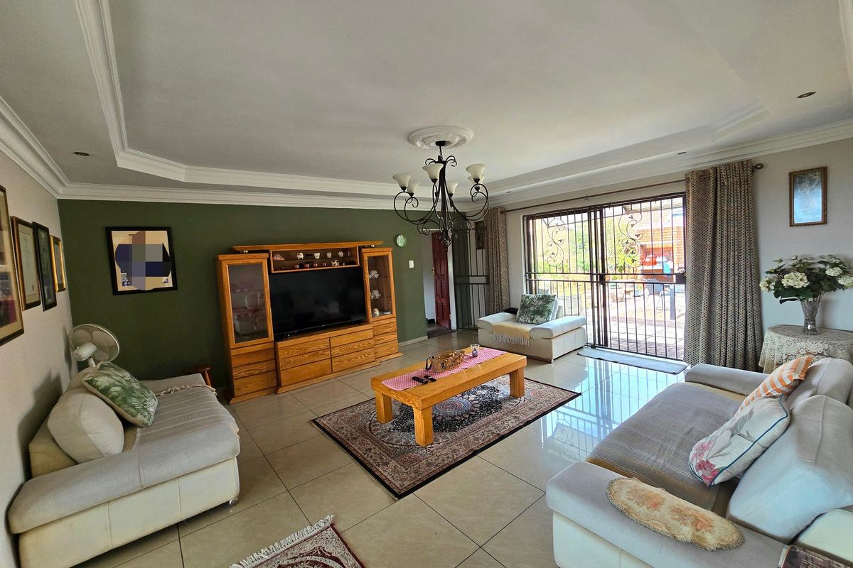 Spacious living room featuring large format floor tiles, a recessed ceiling with downlights, and sliding glass doors providing access to the outdoor area.