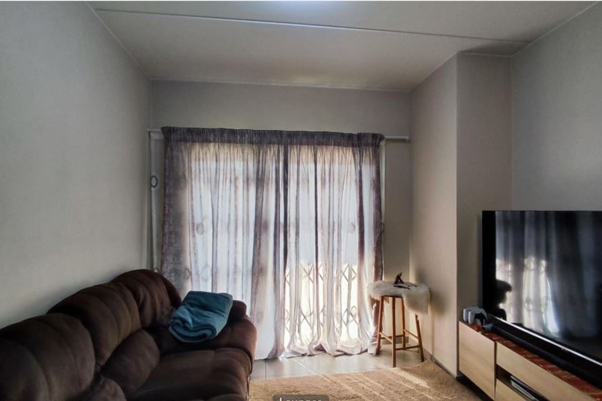 A living room featuring tiled flooring and a sliding glass door with an integrated security gate, providing access to the exterior.